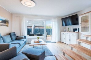 Ein modernes Wohnzimmer mit einer Couch, einem Couchtisch und einem Fernseher.