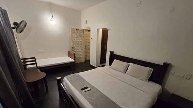 A bedroom with a bed, a chair, a desk, and a wardrobe. - Grace Residency (MADURAI)