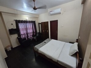 Un dormitorio con cama, escritorio, silla, armario y aire acondicionado.