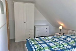 Un dormitori amb llit, taulella de nit, prestatge i armari.