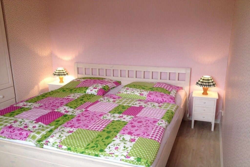 A bedroom with a bed, two bedside tables, and lamps.