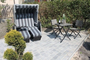 Eine Terrasse mit einer gestreiften Couch, einem kleinen Tisch und zwei Stühlen.