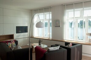 A modern living room with a sofa set, a glass coffee table, and a floor lamp. - Holiday apartment with 1 bedroom (Kappeln Stadt)