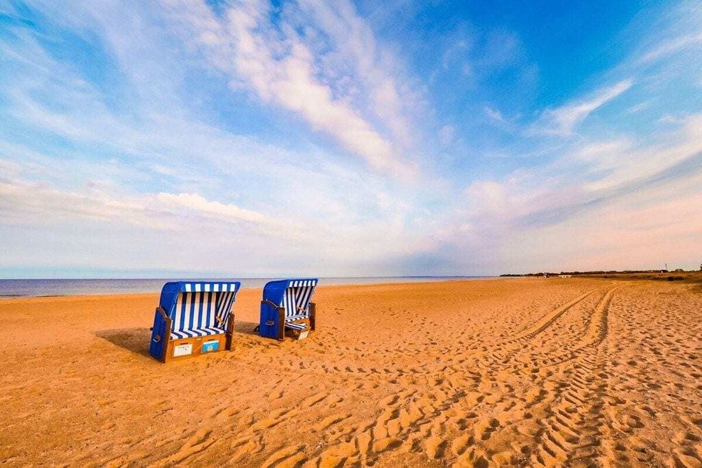 Two beach chairs on a sandy beach with a clear sky.