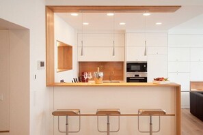 A modern kitchen with a central island, bar stools, and pendant lighting. - Holiday apartment with 1 bedroom (Kappeln Stadt)
