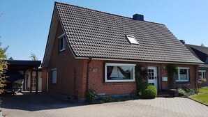 A two-story brick house with a sloped roof, a covered porch, and a visible garage. - Holiday home Seestern (Hasselberg)