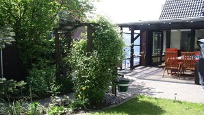A garden area with a pergola, outdoor seating, and a view of a building. - Holiday home Seestern (Hasselberg)