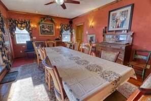 Un comedor con una mesa larga, sillas y un ventilador de techo.