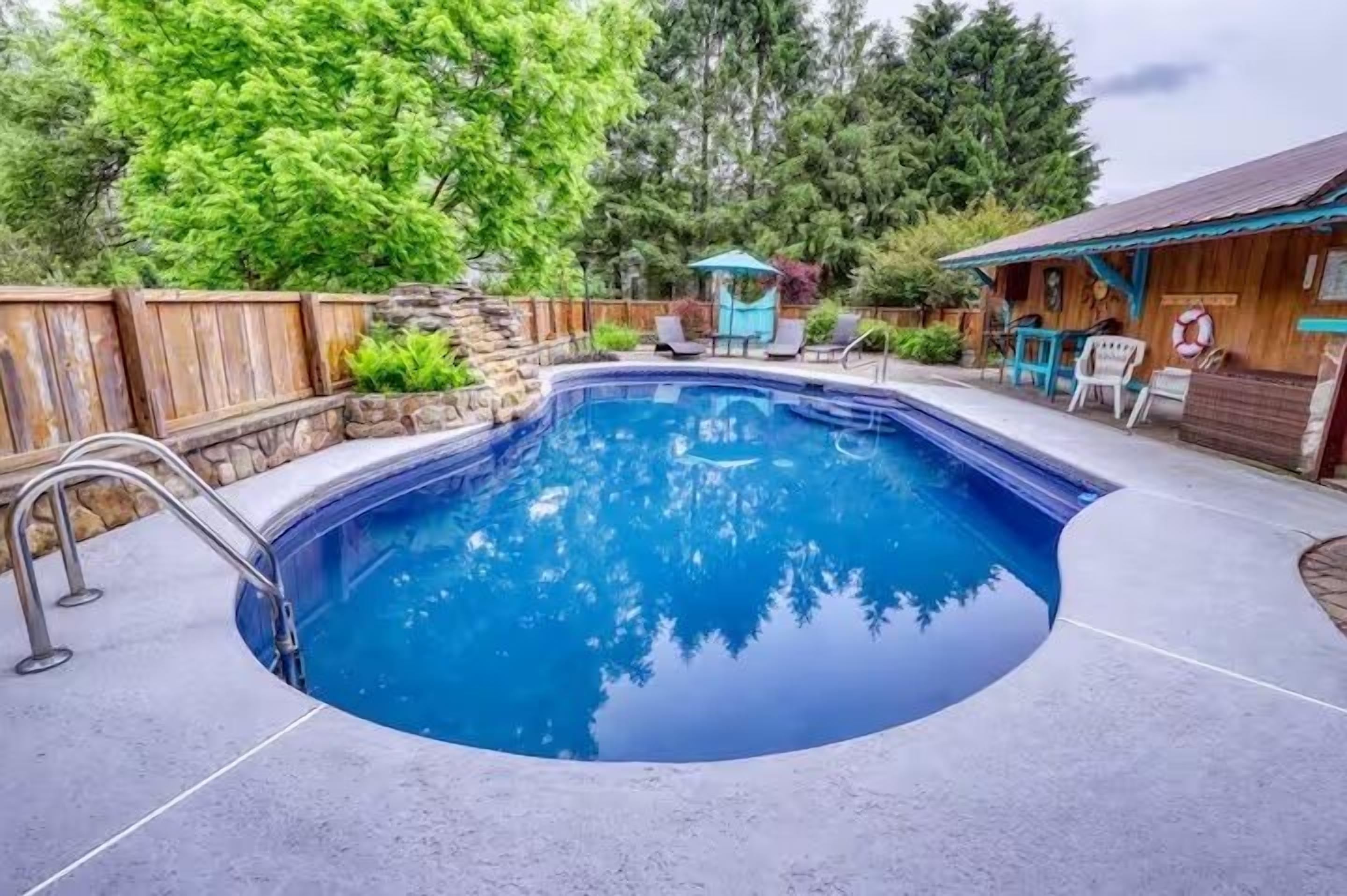 A swimming pool with a wooden deck, a metal ladder, and a wooden fence.
