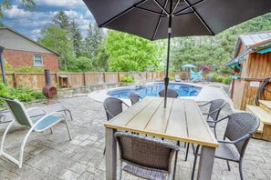 Un patio al aire libre con piscina, mesa y sillas.
