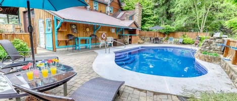 A backyard with a swimming pool, outdoor seating, and a wooden house.