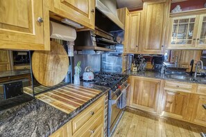 A kitchen with wooden cabinets, a stainless steel range hood, a gas stove, and a granite countertop. - Large Ski Home: Seasonal Pool & Year-Round Hot Tub (Ellicottville)