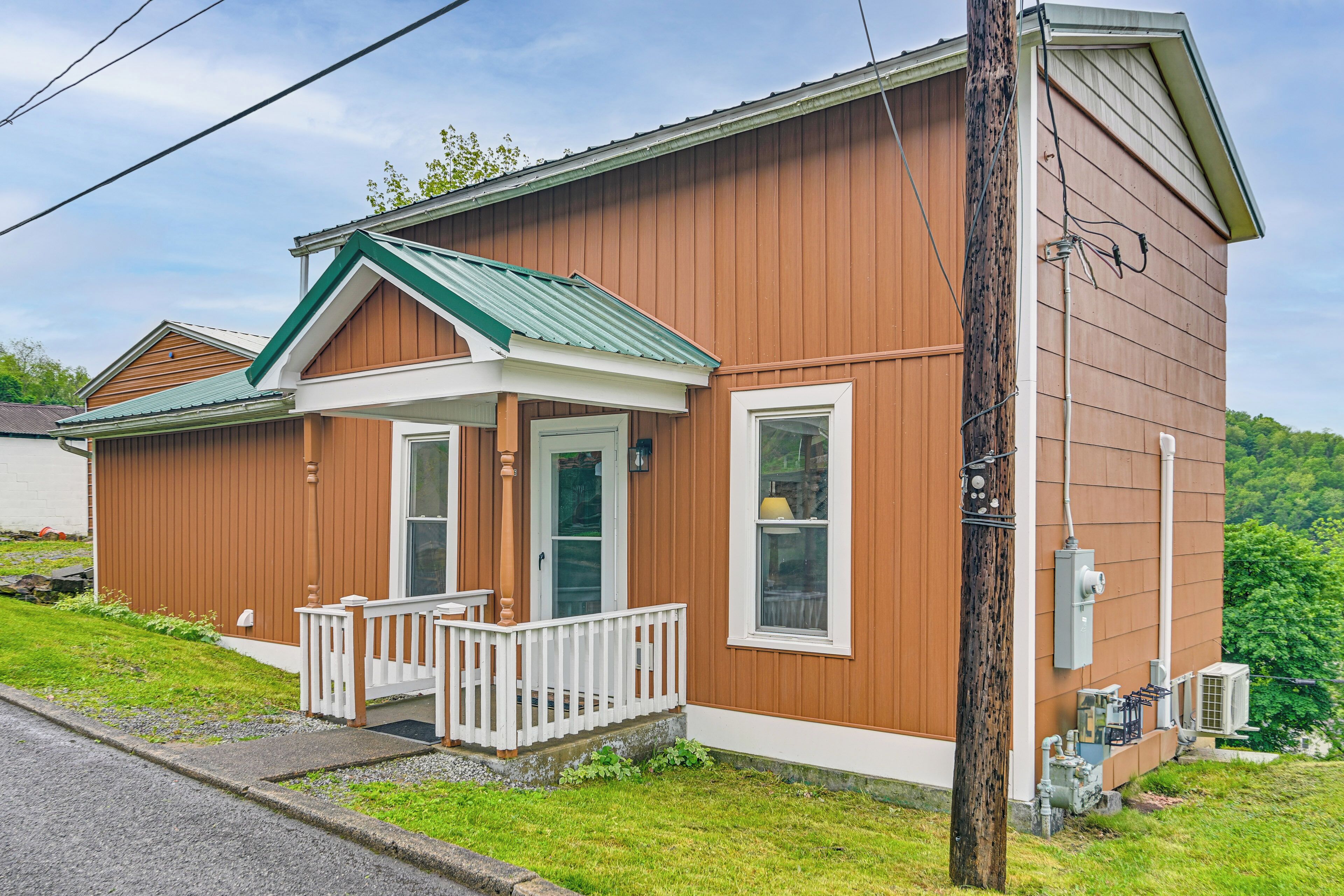 A two-story wooden house with a front porch, a garage, and a utility box.