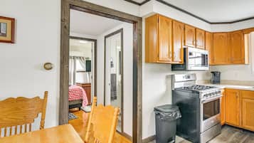 A compact kitchen with wooden cabinets, a stove, and a microwave.