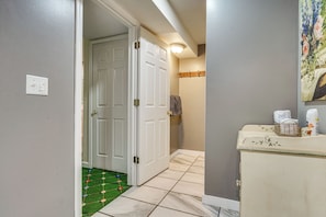 A hallway with a white door, a light switch, and a tiled floor. - Hot Tub Ski Home: Rooster's Den in Ellicottville (Ellicottville)