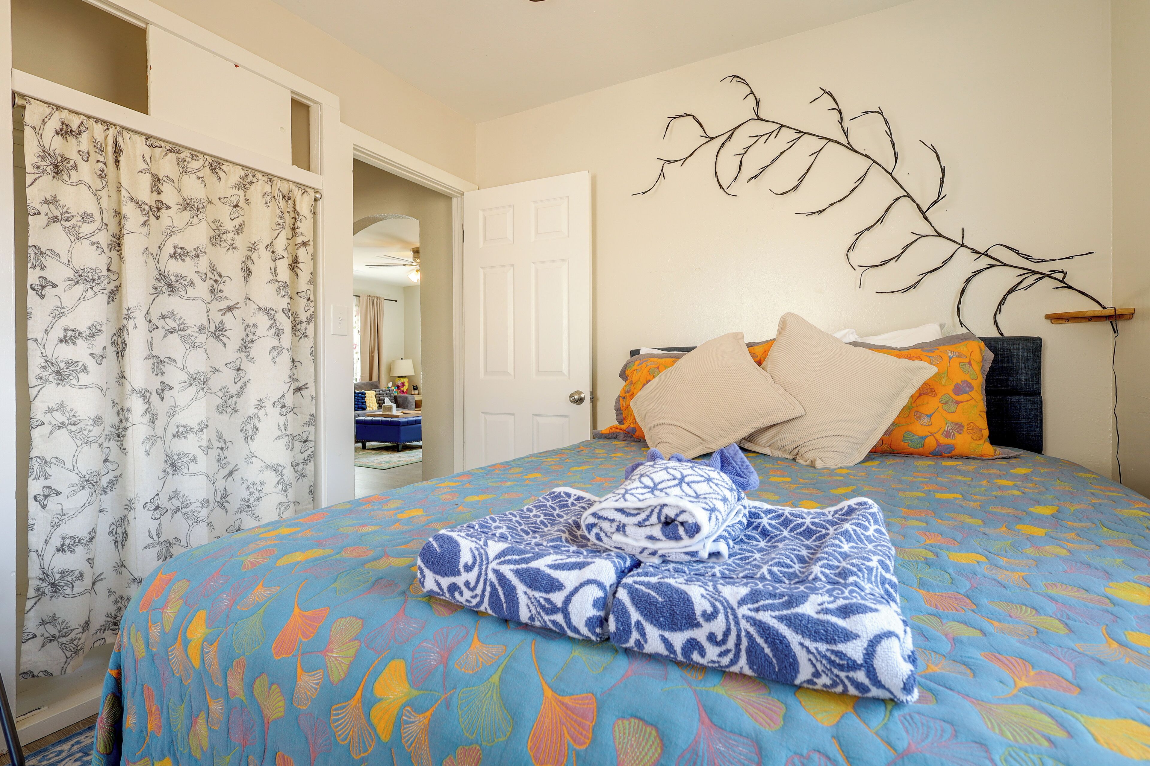 A bedroom with a bed, a door, a mirror, and a wall-mounted branch decoration.