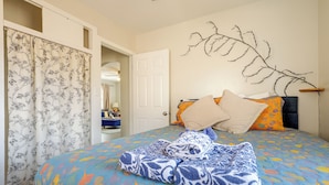 A bedroom with a bed, a door, a mirror, and a wall-mounted branch decoration.