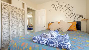 A bedroom with a bed, a door, a mirror, and a wall-mounted branch decoration.