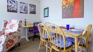 A dining area with a wooden table, four chairs, and a floral armchair.