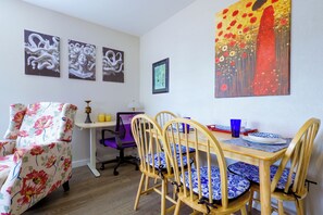 En matplats med ett träbord, fyra stolar och en fåtölj med blommönster.