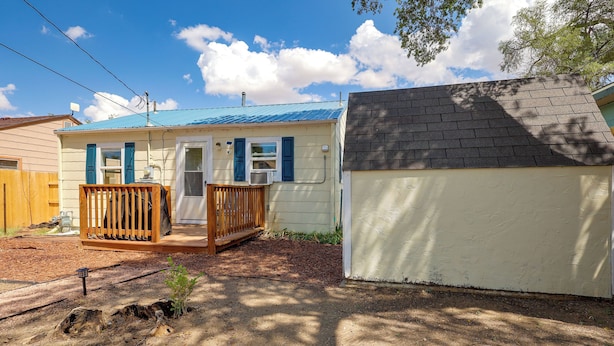 A residential property with a small house, a fenced yard, and a shed.