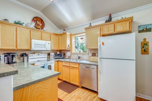 A kitchen with wooden cabinets, a white refrigerator, a microwave, a stove, and a dishwasher.