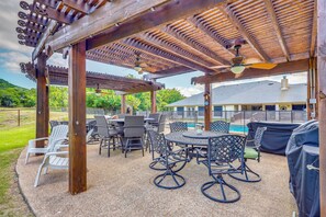 Ein Außenbereich mit Terrasse, einer Pergola, Sitzgelegenheiten und einem Pool.