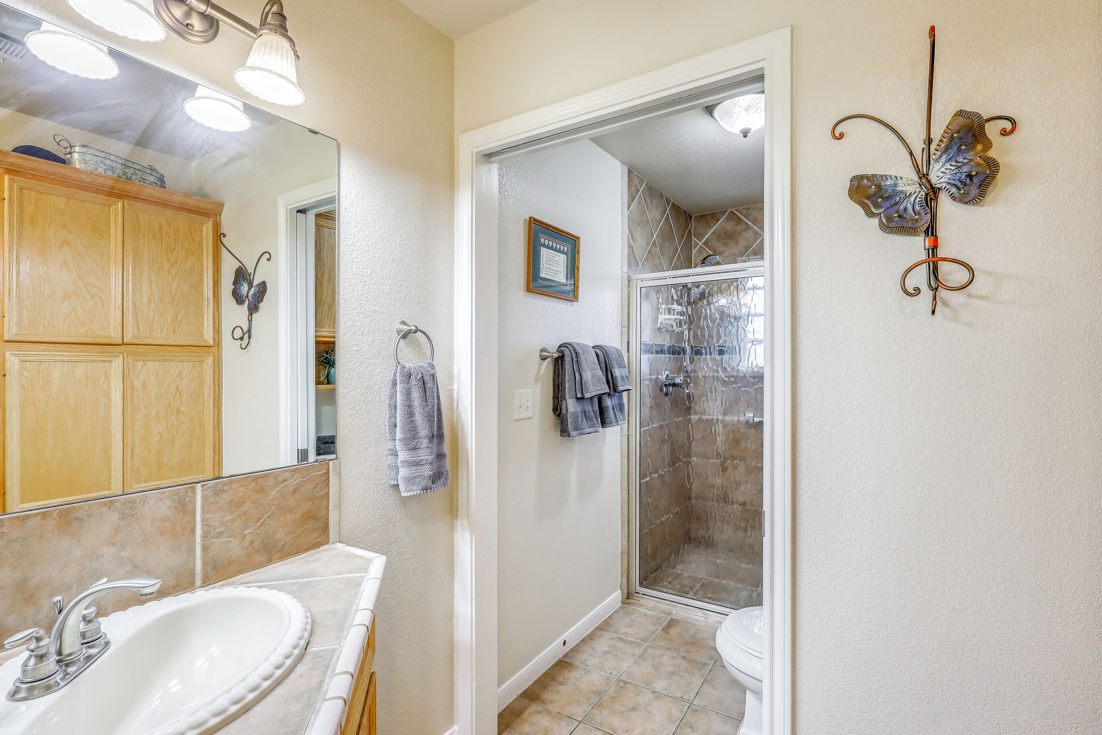 A bathroom with a white sink, a mirror, a shower with a glass door, and a towel rack.