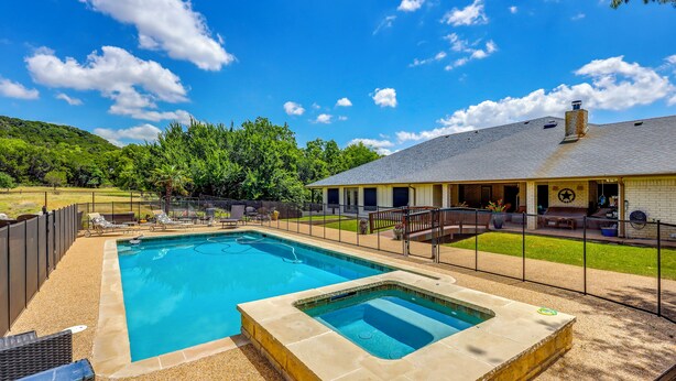 Piscina com ofurô, cercada por um espaço de pátio murado com mobiliário de exterior.