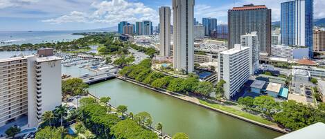 Un paisaje urbano con un río, rascacielos y un puerto deportivo.