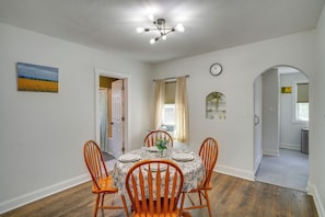 A dining area with a table set for four, wooden chairs, a ceiling light fixture, a clock on the wall, and a painting on the wall. - 3 Mi to Point Beach State Forest: Gem w/ Fire Pit (Two Rivers)