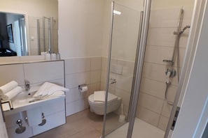 A modern bathroom with a glass-enclosed shower, a white sink with a mirror, and a toilet. - Villa Ocean Time WHG 17 (Haffkurg)