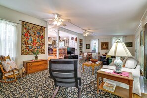 A living room with a fireplace, a television, and a dining area with a table and chairs. - Historic Streamside Farmhouse in Stroudsburg! (Stroudsburg)