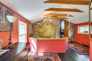 Ein Zimmer mit einer Steinwand, einem großen runden Spiegel und einer roten Akzentwand.