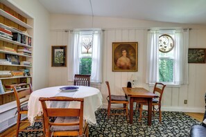 Ein Esszimmer mit rundem Tisch, Stühlen, einem Bücherregal und einem Gemälde.