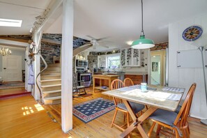 A spacious kitchen with a dining area, wooden flooring, and a spiral staircase. - Historic Streamside Farmhouse in Stroudsburg! (Stroudsburg)