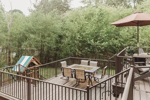 A wooden deck with a table and chairs, surrounded by a metal railing. - Cove Living! Lake Gaston Home w/ Dock & Bar (Bracey)