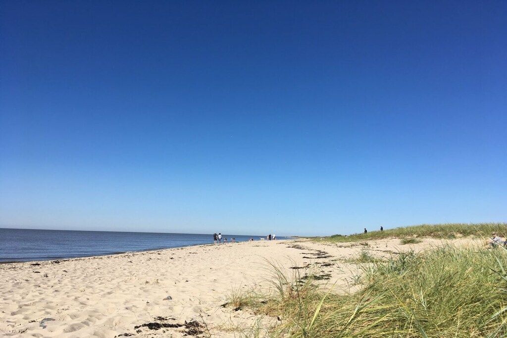 A sandy beach with a clear sky and calm sea.