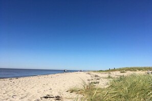 Een zandstrand met een heldere lucht en een rustige zee.