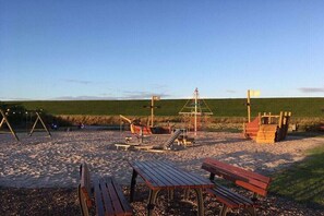 A beach with wooden benches and a swing set. - Holiday apartment in Upleward with balcony (Upleward)