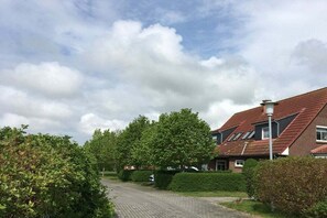 Een woonstraat met huizen, een verharde oprit en een heldere lucht.