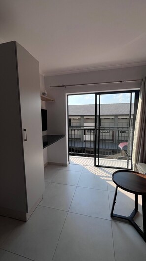 Ein modernes Apartment mit Balkon, Esstisch und Küchenzeile.