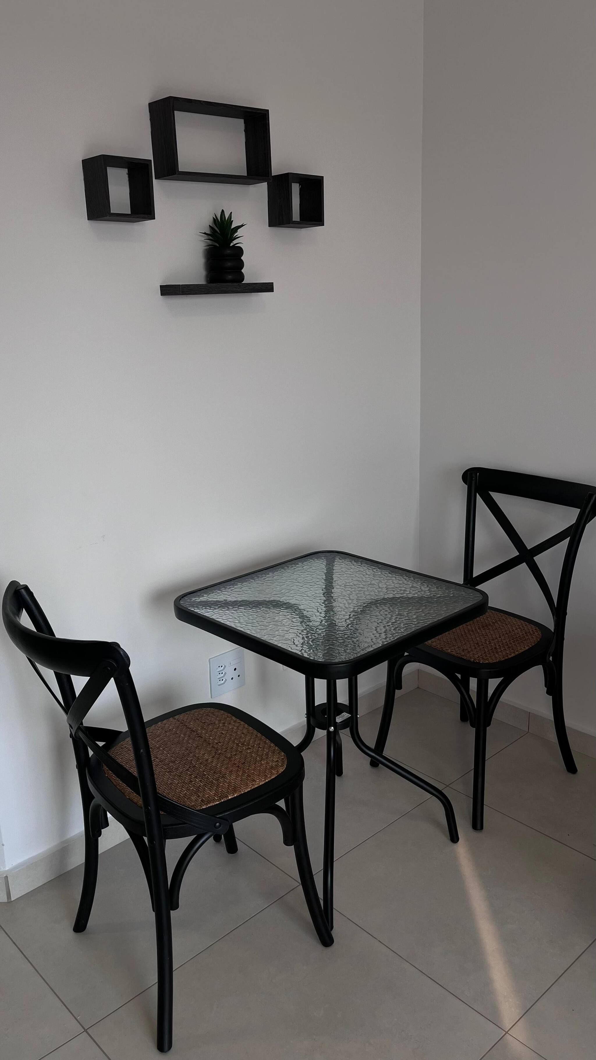 Ein Eckzimmer mit Glastisch und zwei Stühlen mit Sitzgeflecht.