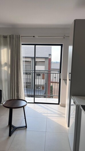 A modern apartment with a balcony, a round table, and a sliding glass door. - Tranquil 1-bedroom Apartment in Roodepoort, South Africa (Johannesburg)