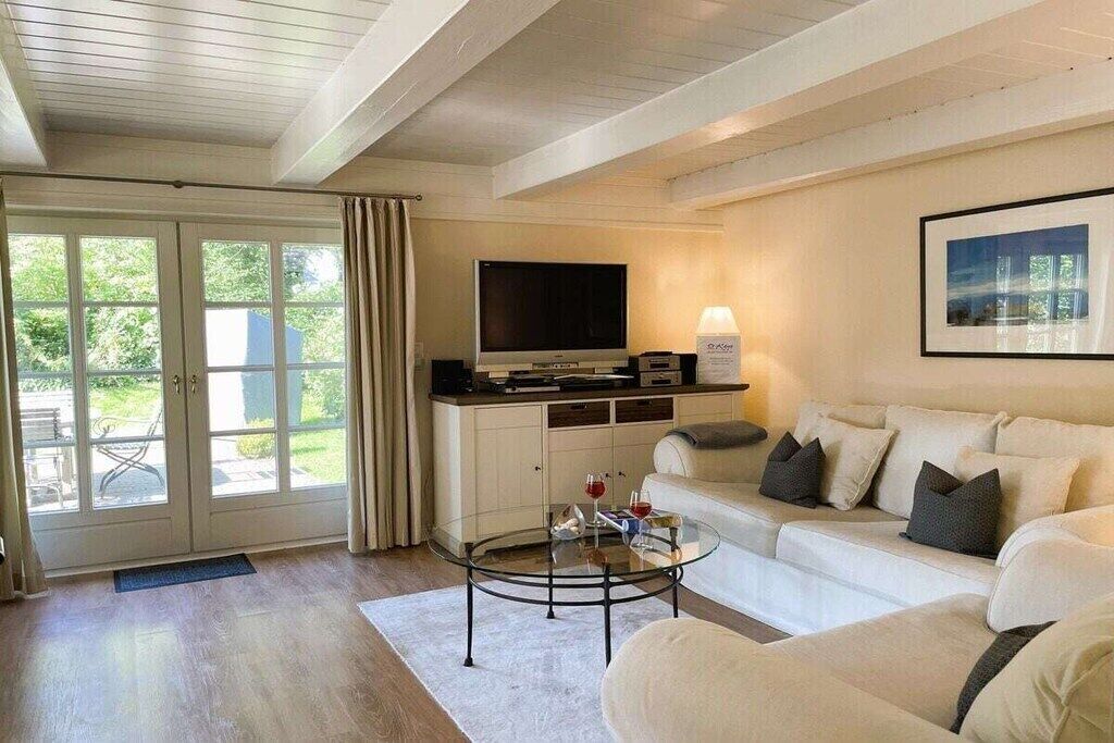 A modern living room with a sofa, a glass coffee table, a flat-screen TV, and a door leading to a patio.