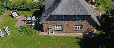 A house with a steeply pitched roof, a brick facade, and a well-maintained lawn.