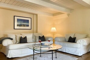 A living room with a white sofa, a glass coffee table, a framed picture on the wall, and a floor lamp. - Holiday home with 3 bedrooms (Süderende)