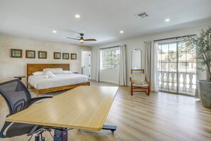 Ein Hotelzimmer mit Bett, Schreibtisch, Stuhl, Deckenventilator und einem großen Fenster mit Aussicht.
