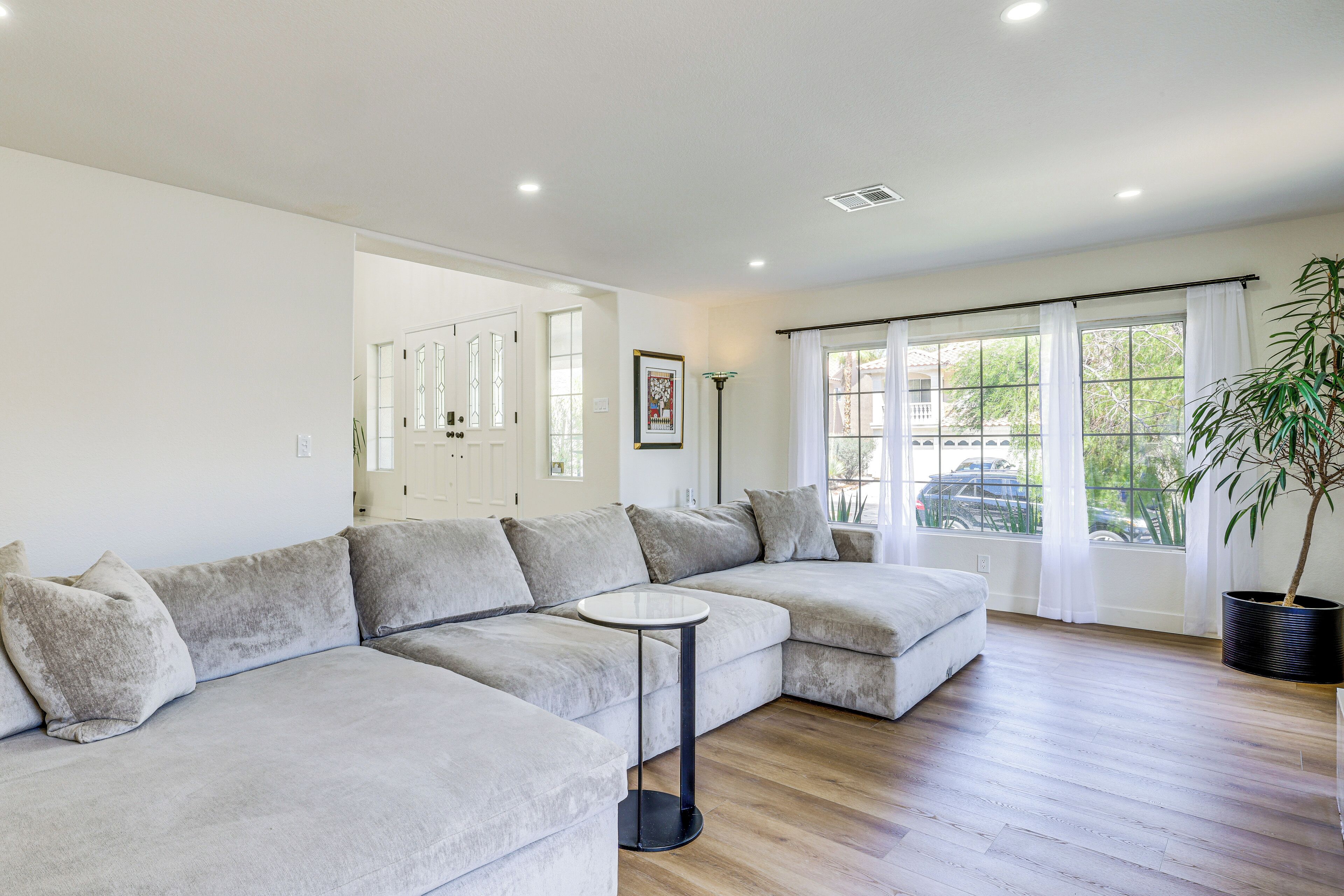 A modern living room with a sectional sofa, a small round table, and a potted plant.