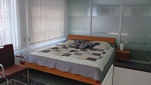 A bedroom with a bed, a chair, a nightstand, and a window with blinds. - Holiday home in Wingst with swimming pool (Wingst)